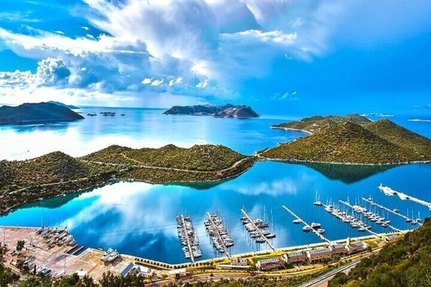 A marina with boats, a clear blue sky, and distant islands. 1