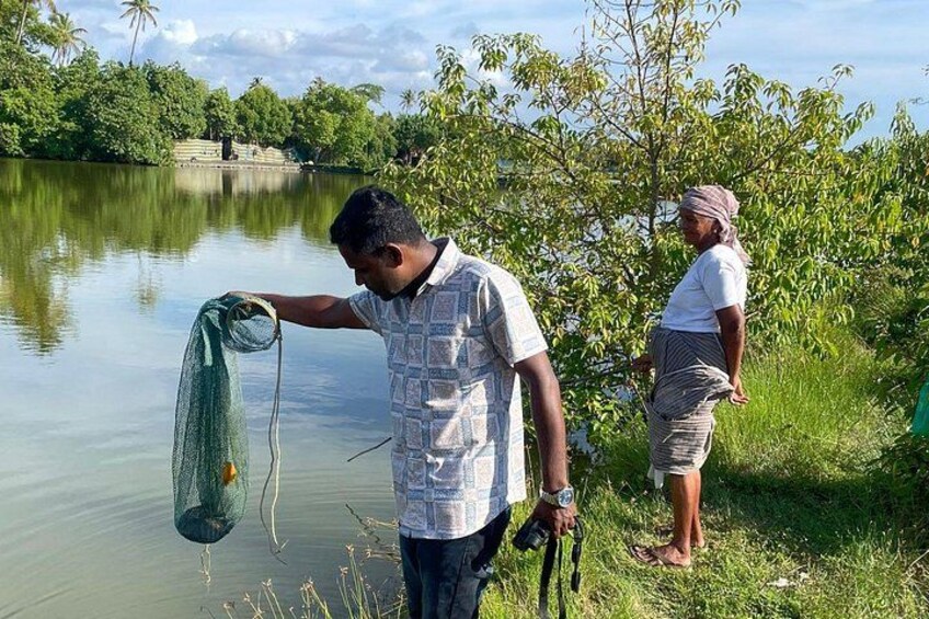 A person holding a fishing net by a calm lake with trees in the background. 2