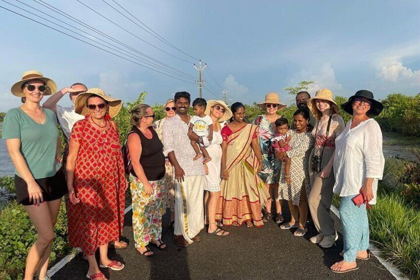 A group of people standing on a road with greenery on both sides. 3