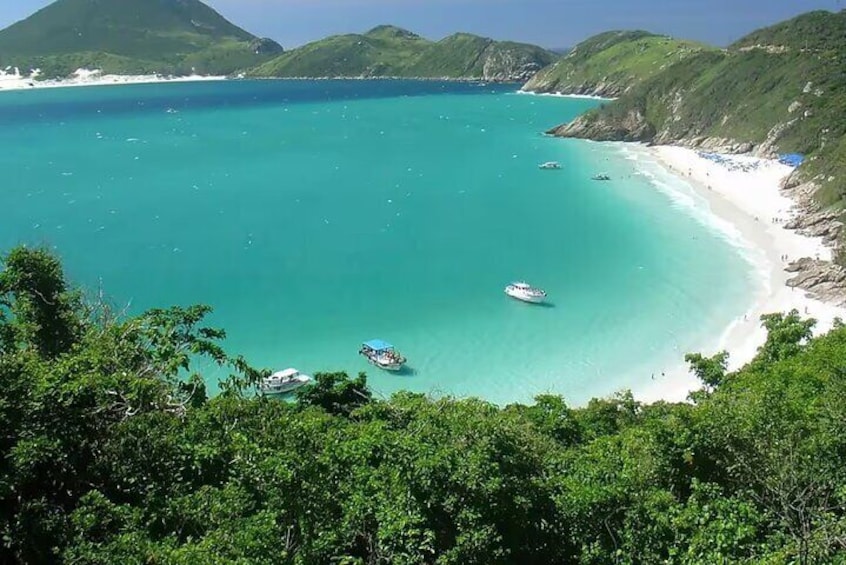 A turquoise sea, a white sandy beach, and lush green hills. 1