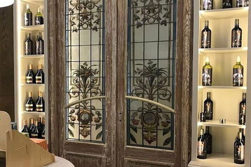 A wine cellar with shelves of wine bottles and a decorative glass door. 2