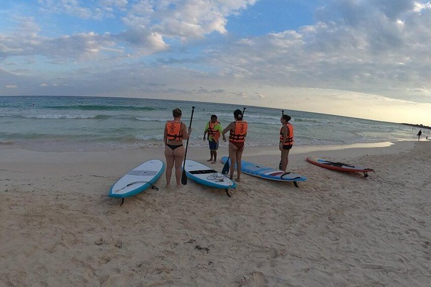 Una playa con tablas de remo y gente con chalecos salvavidas. 4