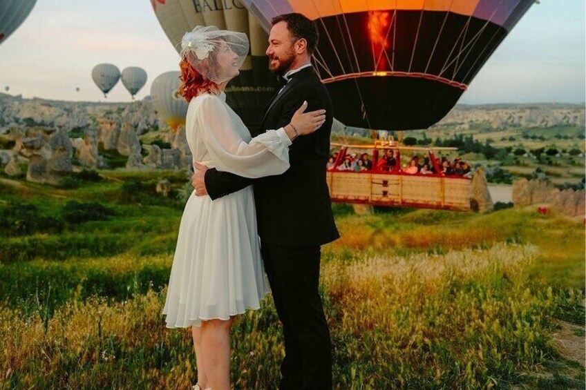 A couple embracing in front of a hot air balloon with a scenic landscape in the background. 5
