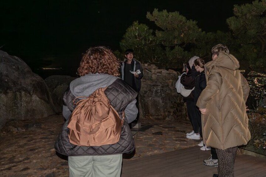 A group of people standing on a wooden boardwalk at night. 5