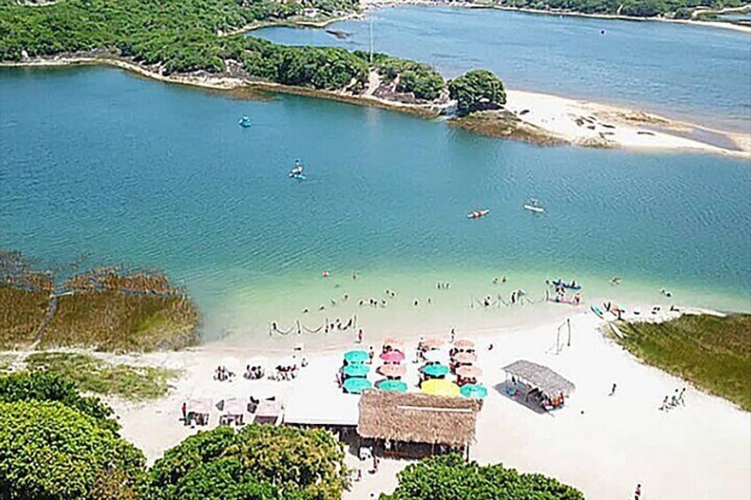 A beach with clear water, umbrellas, and people. 2