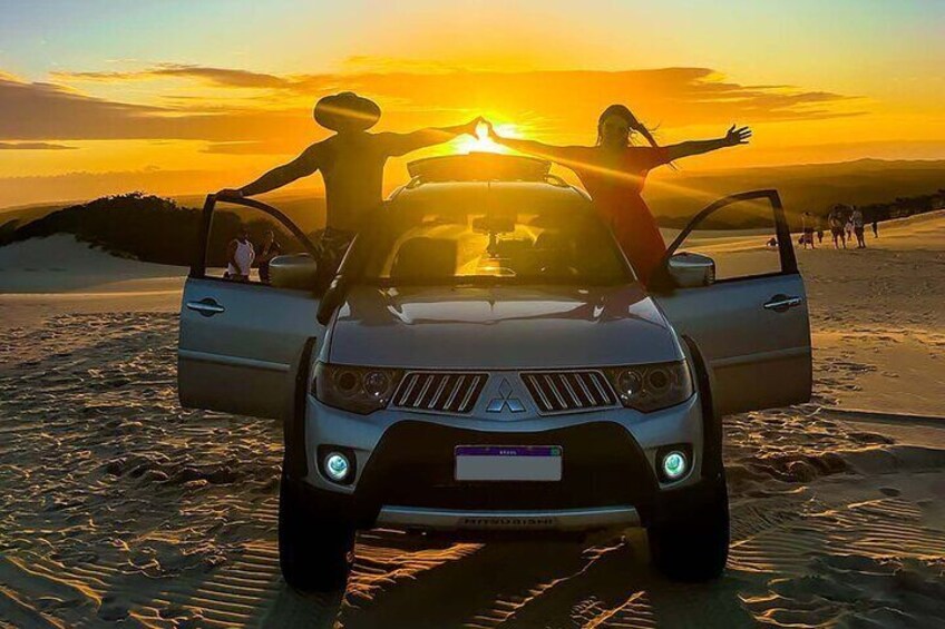 A vehicle with its doors open on a beach at sunset. 5
