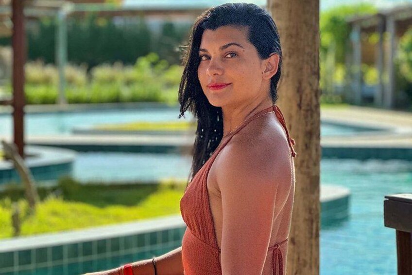 A person standing by a pool with a clear view of the water and surrounding greenery. 4