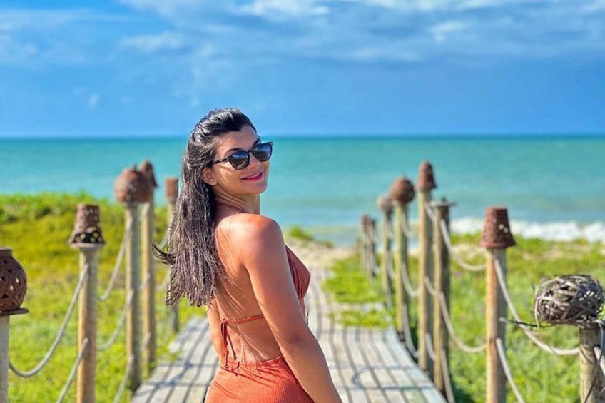 A person standing on a wooden boardwalk with a beach and ocean in the background. 5