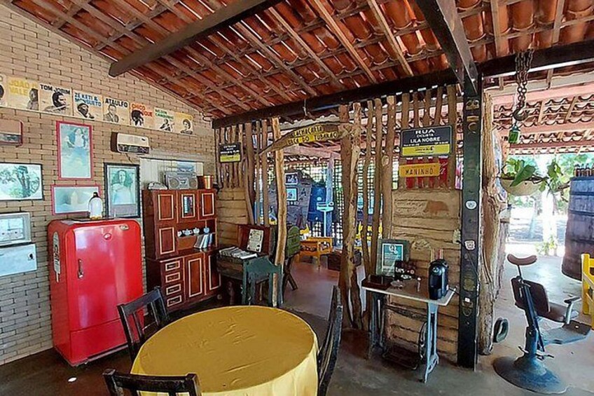 A rustic interior with a wooden ceiling, a red refrigerator, a yellow table, and various signs and decorations. 2