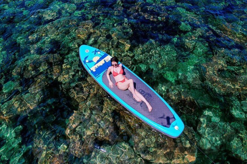 A person lying on a surfboard in clear water. 2