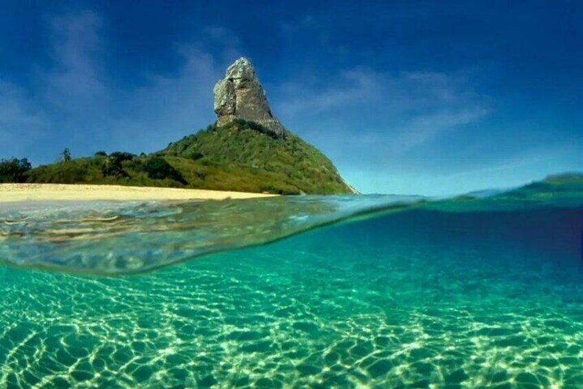 A clear underwater view of a beach with a prominent rock formation on a small island. 5