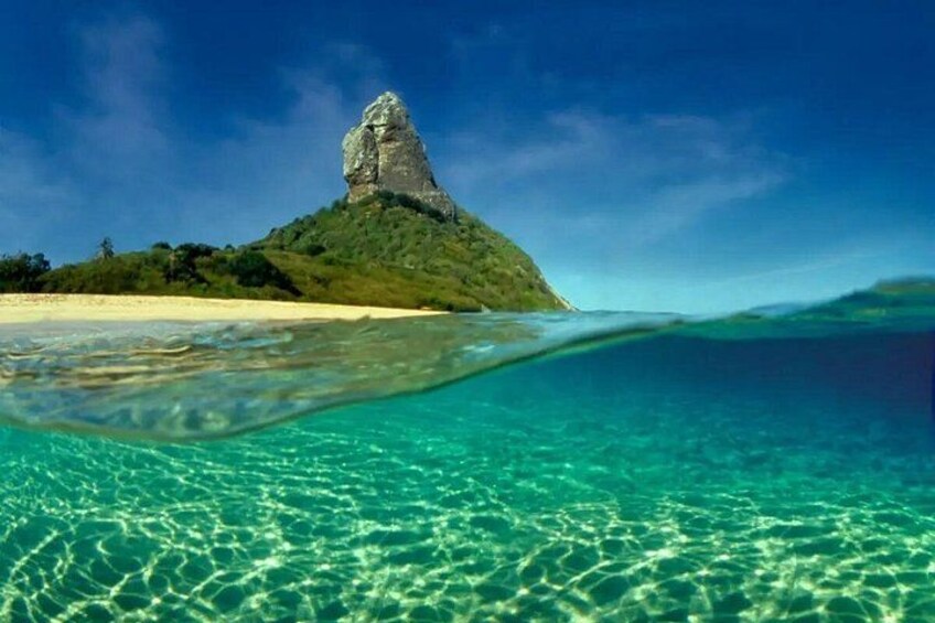 A clear blue sea, a sandy beach, and a rocky hill with vegetation. 3