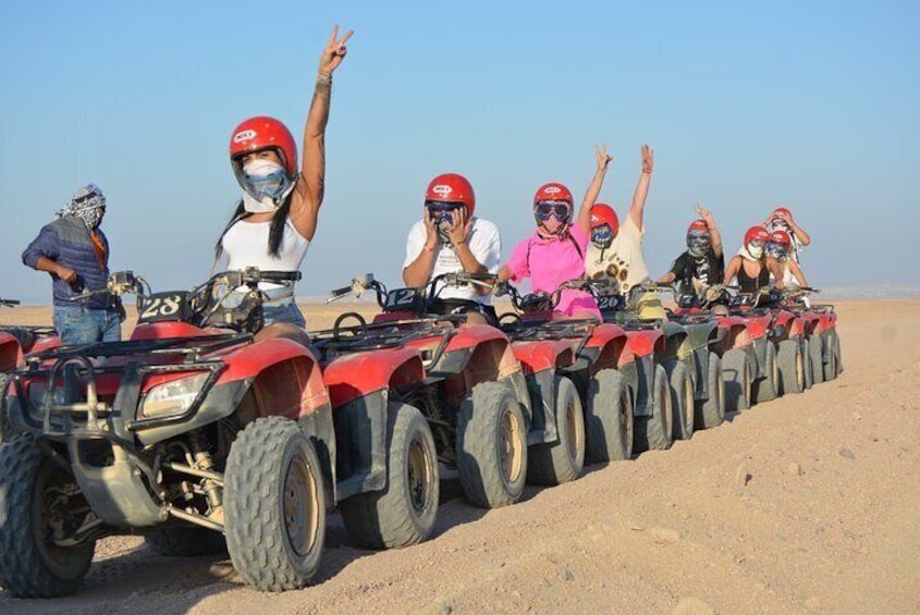 A group of people on ATVs lined up on a sandy slope. 3