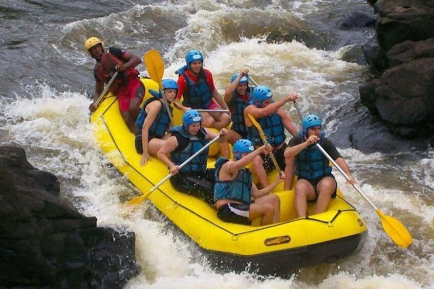 A group of people in a yellow raft navigating a river with rapids. 2
