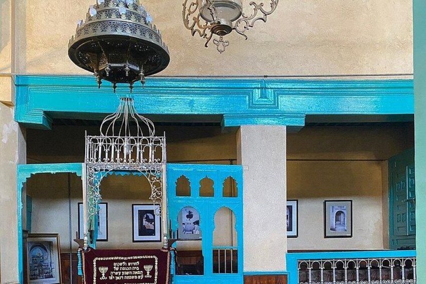 A building with turquoise trim, a decorative metal gate, and a hanging bell. 4