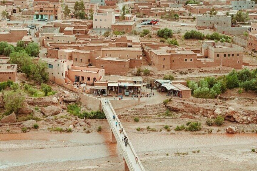 A desert town with adobe buildings, a bridge, and sparse vegetation. 4