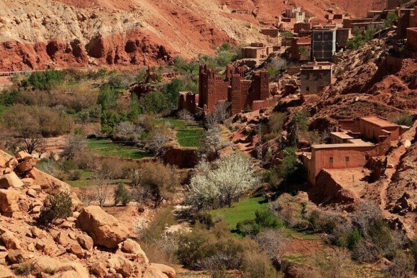A rugged landscape with terraced buildings nestled among red rock formations and sparse vegetation. 2
