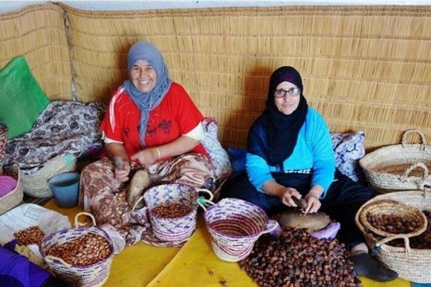 Two women sitting on a woven couch surrounded by baskets of nuts and grains. 3
