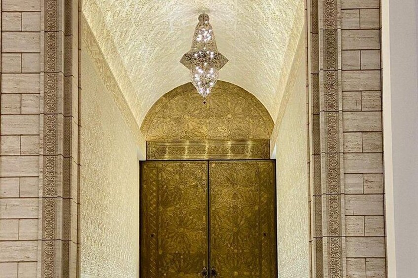 An arched doorway with intricate patterns and a chandelier above. 2
