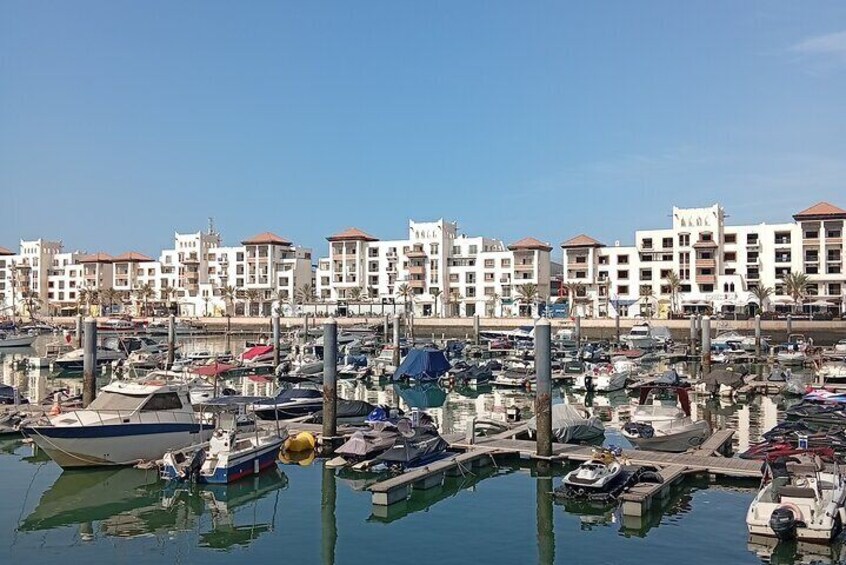 A marina with boats docked, a clear sky, and buildings in the background. 3