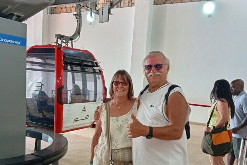 A red and white bus with Arabic text, a man and woman standing in front of it, and a sign that reads 'Doppelmayr.' 5