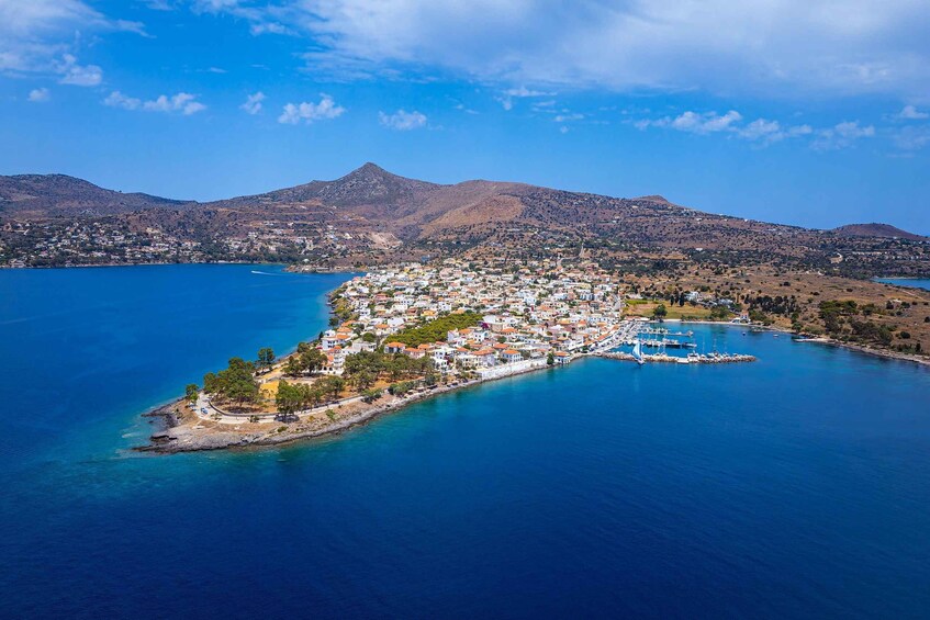 An aerial view of a coastal town with a harbor, surrounded by mountains and a clear blue sea. 1