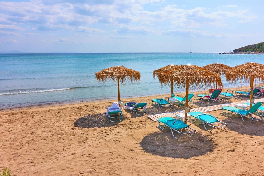 A beach with thatched umbrellas, sun loungers, and a calm sea. 4