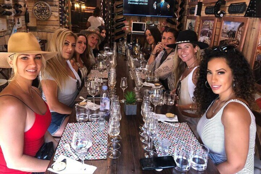 A group of people seated at a bar with wine glasses and bottles. 5