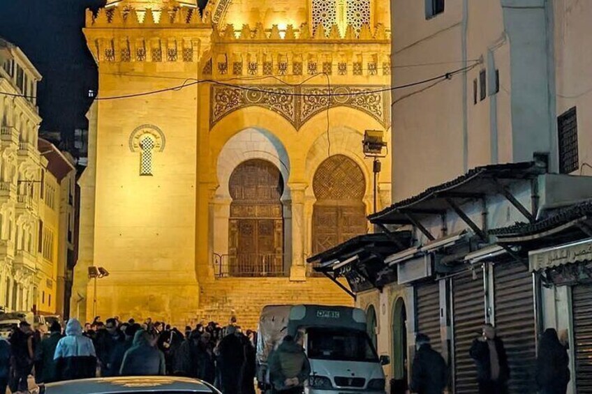 A historic building with ornate arches and a crowd gathered outside at night. 4