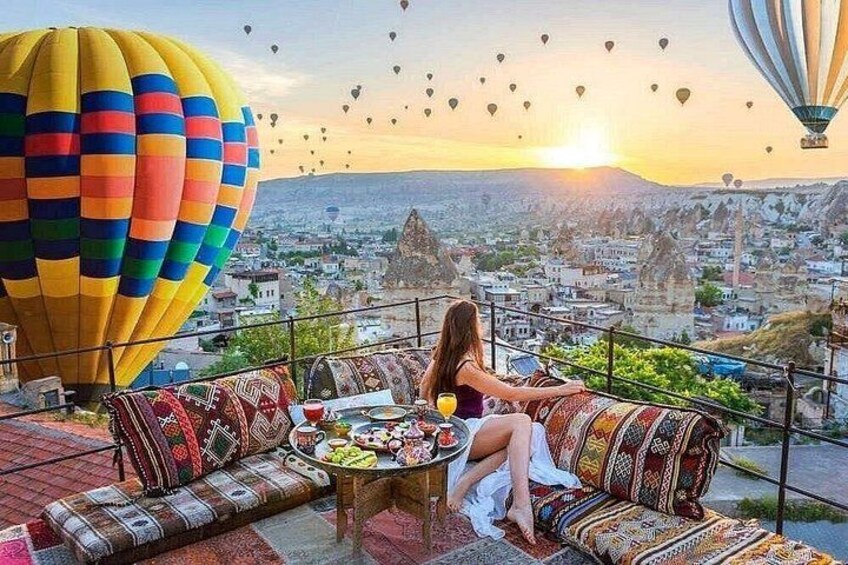 A woman sitting on a sofa with a cityscape and hot air balloons in the background. 2
