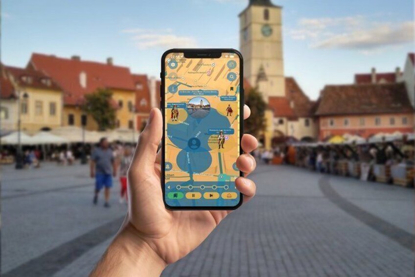 A hand holding a smartphone displaying a map with a blue figure and icons, in front of a town square with buildings and a clock tower. 1
