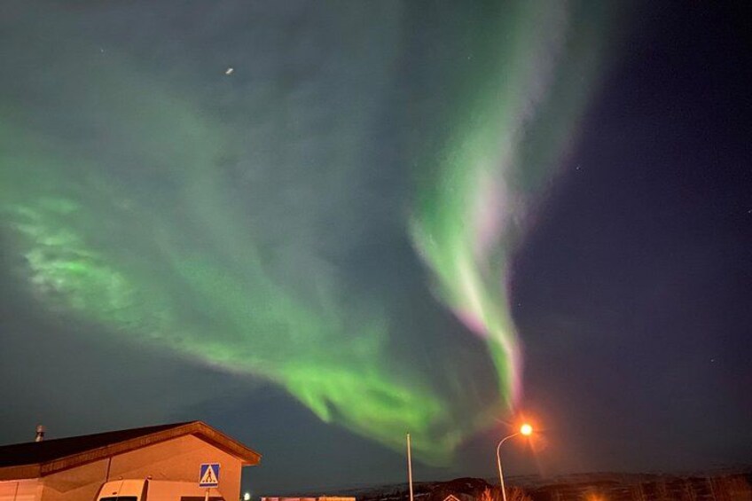 The aurora borealis over a rural landscape with a building and street lights. 4