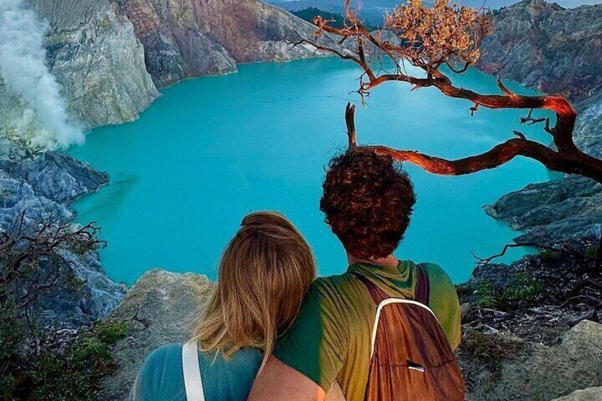 Two people overlooking a turquoise lake surrounded by rocky terrain. 4