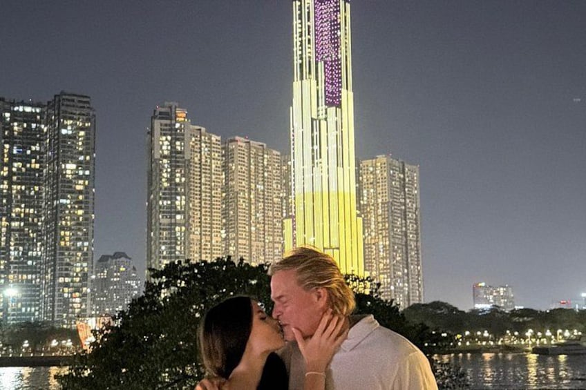 A couple kissing in front of a cityscape with illuminated buildings at night. 2