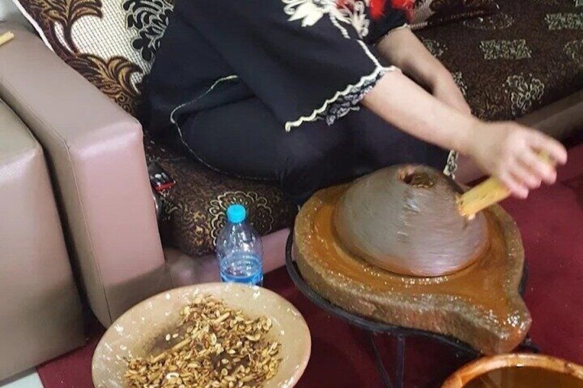 A person sitting on a couch, using a wooden tool to mix contents in a bowl. 1