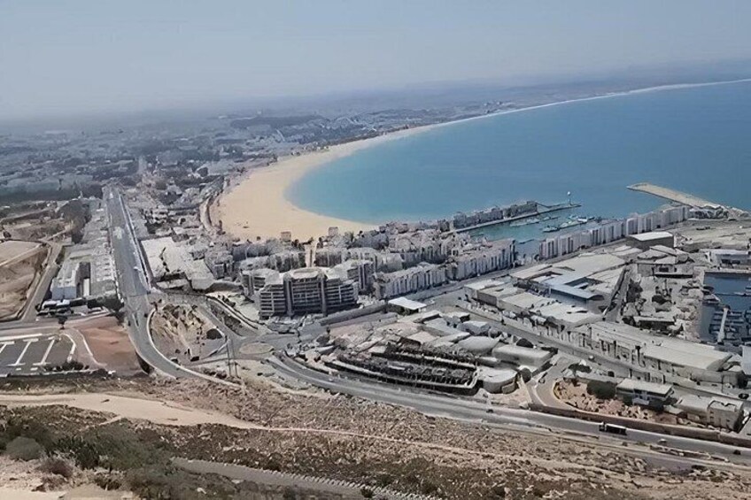 A coastal cityscape with a beach, a marina, and a highway. 3