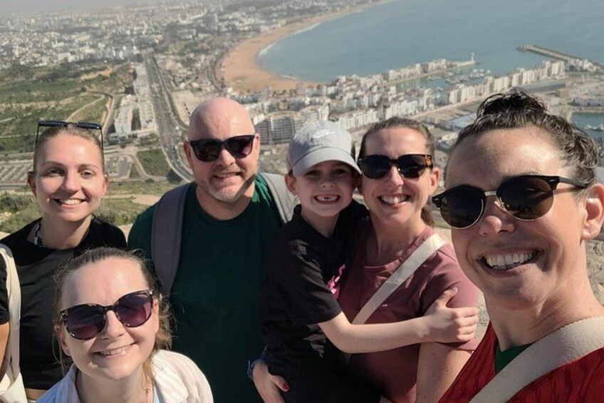 A group of people on a high vantage point overlooking a coastal cityscape with a beach and urban areas. 1