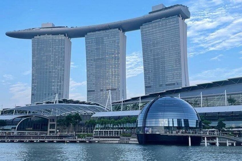 A modern architectural structure with a distinctive cantilevered top, a large dome, and a waterfront setting. 4
