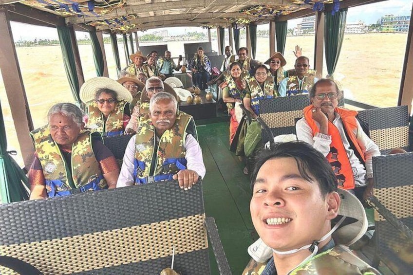 A group of people on a boat with wicker seats and a covered upper deck. 5