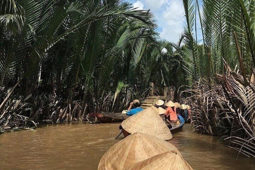 A river with people paddling in a canoe, surrounded by tall palm trees. 3
