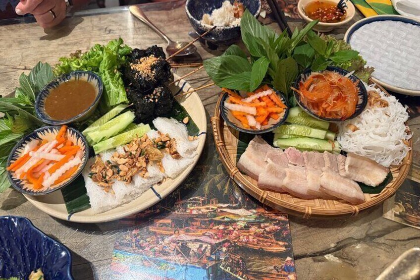 A table with various Vietnamese dishes, including rice, vegetables, and meat, along with several small bowls of sauces. 4