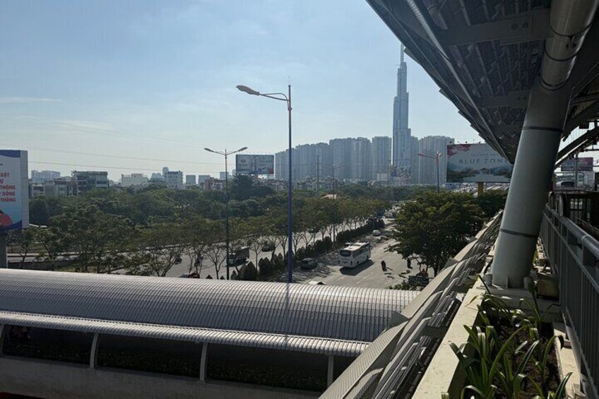 A cityscape with a prominent skyscraper, a covered pedestrian walkway, and a billboard advertising 'BLUE ZONE.' 5