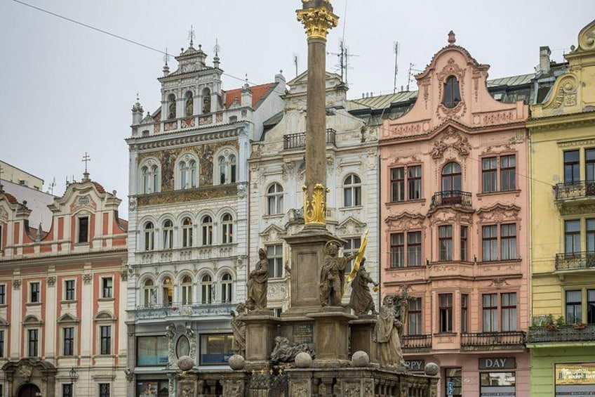 Una hilera de edificios históricos coloridos, con fachadas ornamentadas y una estatua central. 2