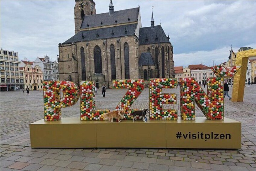 A historic church with a large, colorful sign in the foreground. 1