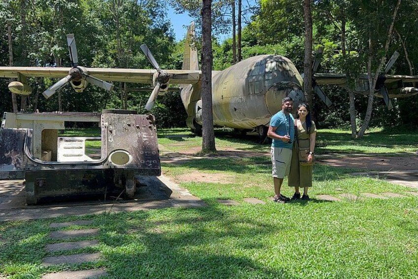 A military vehicle and an aircraft in a grassy area with trees in the background. 2