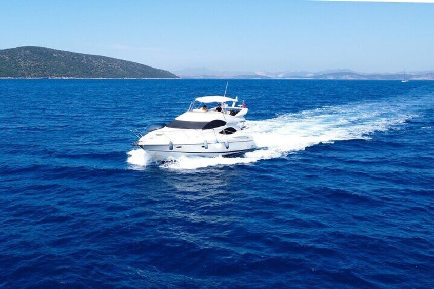 A white yacht cruising on a deep blue sea with a distant shoreline and a clear sky. 1