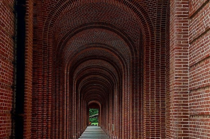 A brick tunnel with a green sign at the end. 1