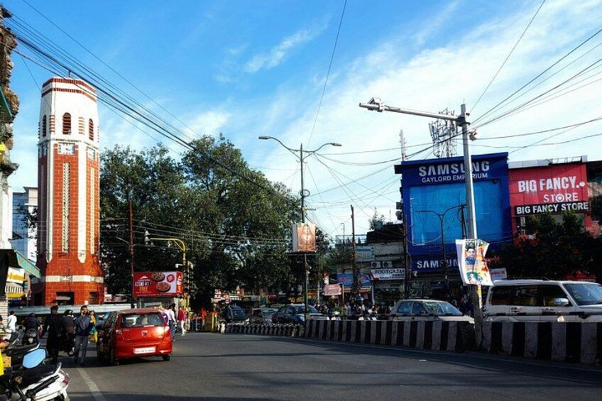 A busy urban street with a prominent clock tower, a Samsung store, and a Big Fancy Store. 2