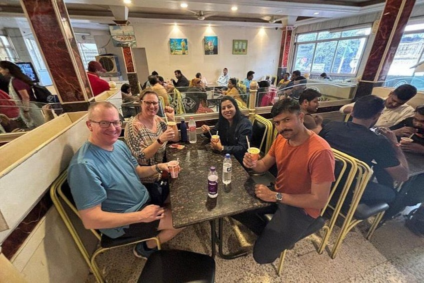 A group of people seated at a table in a restaurant with a marble countertop and gold chairs. 3
