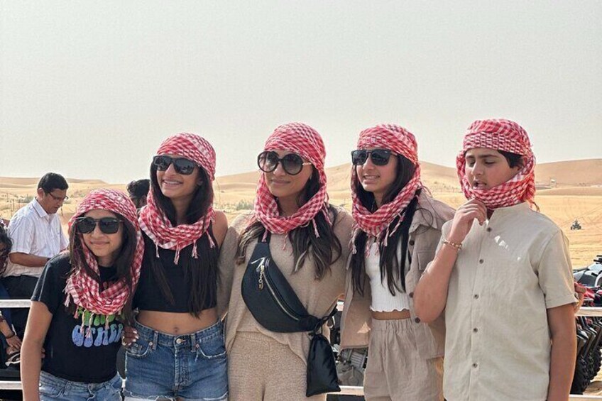 A group of people wearing red and white headscarves standing in a desert landscape. 4